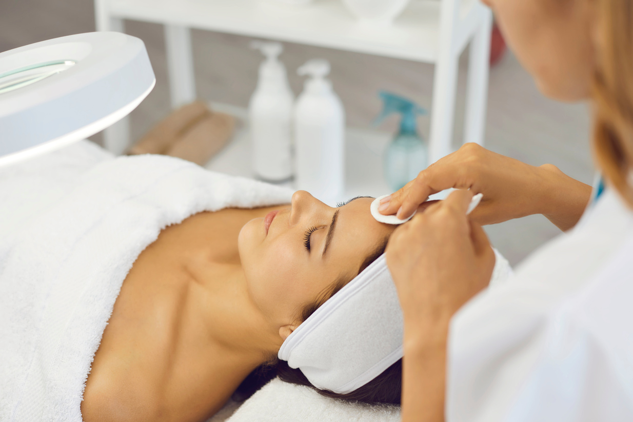 Cosmetologist Cleaning Woman Facial Skin with Cotton Pads before Beauty Treatment